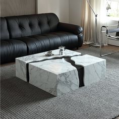 a marble coffee table sitting on top of a rug in front of a black couch