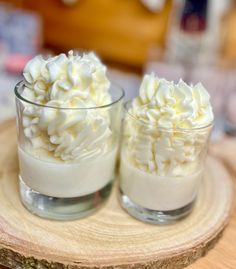 two glasses filled with whipped cream on top of a wooden table