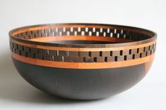 a black and brown bowl on a white surface with wooden strips in the bottom half