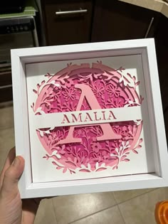 a person holding up a pink paper cut out with the word maala in it