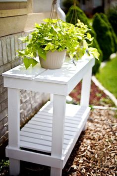 a potted plant sitting on top of a white table next to a brick wall