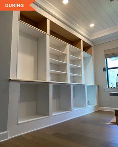 an empty room with white shelving and wood flooring in the middle of it