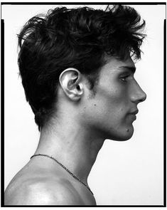 black and white photograph of a young man with ear piercings on his ears, looking to the side