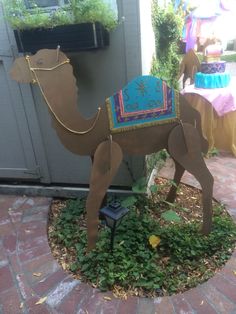 a paper mache camel is sitting on the ground in front of a building and table