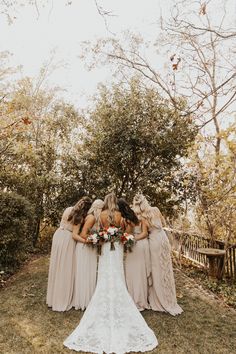 a group of bridesmaids standing in front of a tree with their backs to the camera