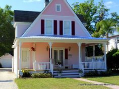 a pink house with white trim and red shutters on the front porch is shown