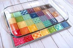 a glass tray with different colored patchwork squares in it on a white wood floor