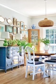 a dining room table and chairs with pictures on the wall behind them, along with potted plants