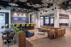 a large open concept office with seating and tables in front of a bar area that has chairs around it