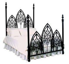 a black iron bed with white sheets and pillows