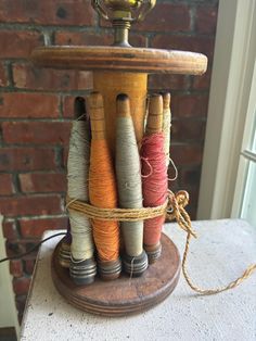 several spools of thread are tied together on a table next to a brick wall