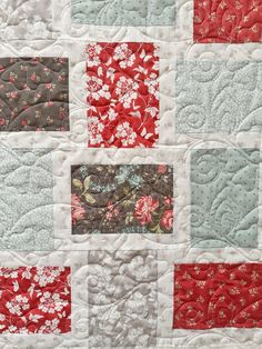 a close up of a quilt with red and white flowers on it's center