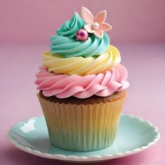 a cupcake on a plate with icing and decorations in pastel blue, pink, yellow and green