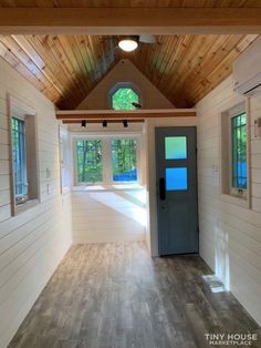 the inside of a tiny house with wood floors and windows on each side of the door