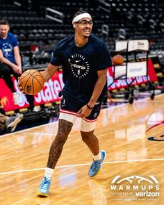 a man with a basketball in his hand is on the court and smiles at the camera