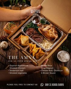 a person holding a box with food in it on top of a wooden table next to other items