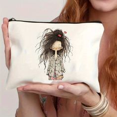 a woman holding up a white zippered pouch with a drawing of a girl on it