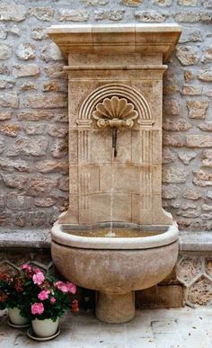 a stone fountain in front of a brick wall