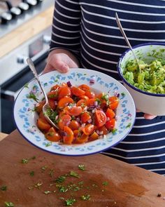 a person holding a bowl of food on top of a wooden table