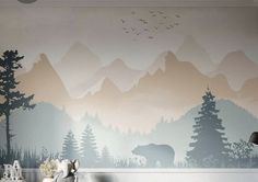 a bedroom with mountains and trees painted on the wall, along with a teddy bear