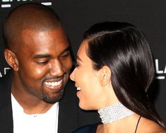 a man and woman smile at each other as they pose for a photo on the red carpet