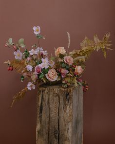 a wooden vase filled with flowers on top of a table next to a brown wall