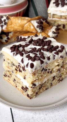 a piece of cake on a plate with chocolate chips and frosting, sitting on a table