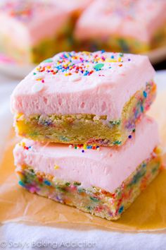 two pieces of cake with pink frosting and multicolored sprinkles