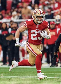 a football player running with the ball in his hand and people watching from the stands behind him