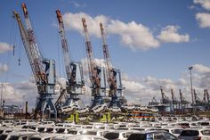 many cars are parked in a lot with cranes on top of them and blue sky above