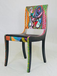 a colorful chair sitting on top of a white floor next to a white wall with a painting on it