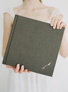 a woman holding a book in her hands with the cover partially closed to reveal an image