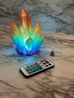 a remote control sitting on top of a table next to a colorful lamp and remote