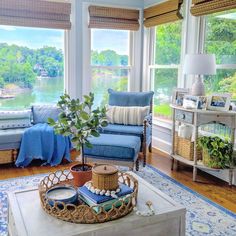 a living room filled with lots of furniture and windows covered in blue blankets, pillows and throw pillows