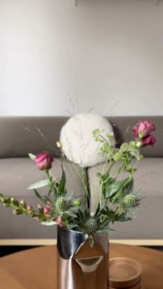 a vase filled with flowers sitting on top of a wooden table next to a couch