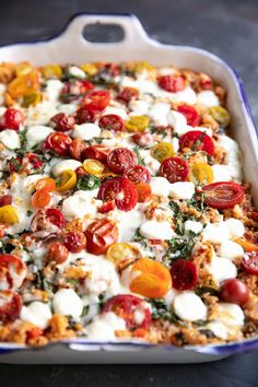 a casserole dish with tomatoes, mozzarella and cheese