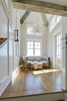 a living room filled with furniture and a chandelier hanging from the vaulted ceiling