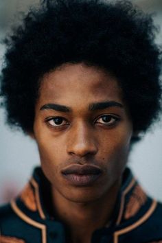 a young man with an afro looks at the camera