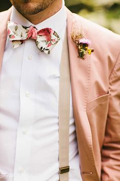 a man wearing a pink suit and bow tie with flowers on his lapel collar