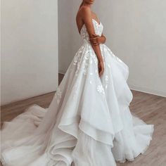 a woman in a white wedding dress standing on a wooden floor next to a wall