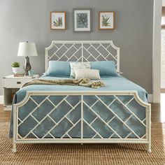 a white bed with blue sheets and pillows in a gray room next to two framed pictures on the wall