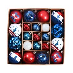 an open box filled with christmas ornaments on top of a white surface and red, white, and blue baubles