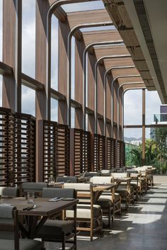 an empty restaurant with wooden tables and chairs in front of large windows that have shutters on them