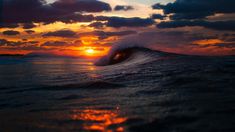 the sun is setting over an ocean wave