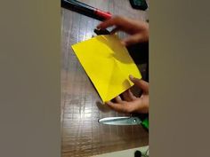 someone is cutting up a yellow piece of paper