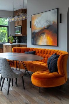 an orange couch sitting in front of a wooden table with two chairs next to it