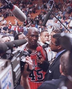 the basketball player is surrounded by reporters and microphones