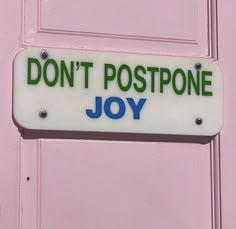 a sign that says don't postpone joy hanging on a door with pink paint