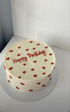 a white cake with red hearts on it and the words happy birthday written on top