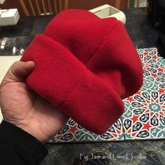 a hand holding a red object on top of a table